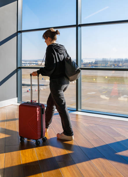 istock Teenage girl walking through the gate and pulling wheeled suitcase 2174584439