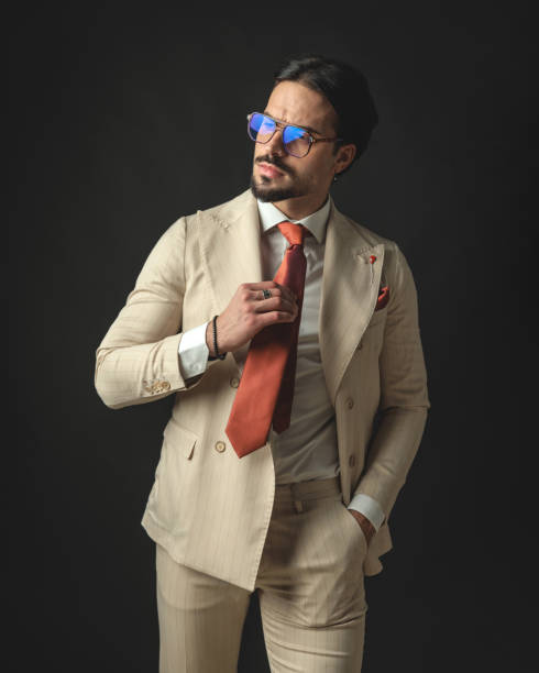 istock relaxed young man in beige suit fixing his red tie 2174588524