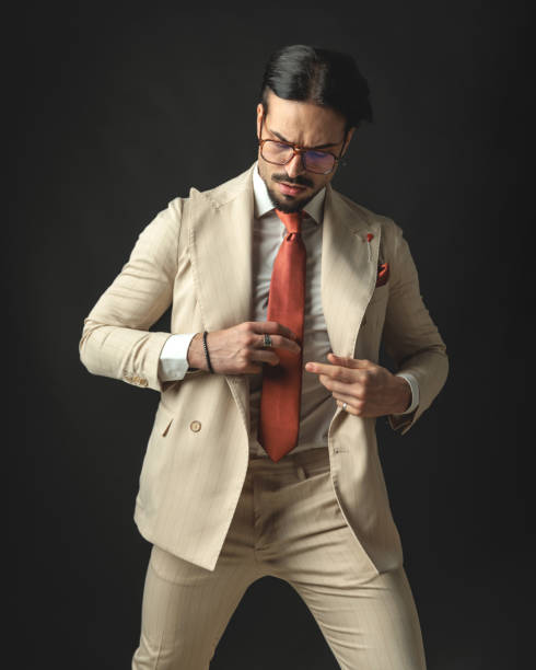 istock attractive fashion man buttoning beige suit while looking down 2174589441