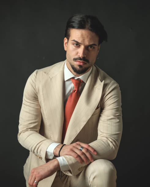 istock handsome guy model in beige suit resting arm on knee 2174589623