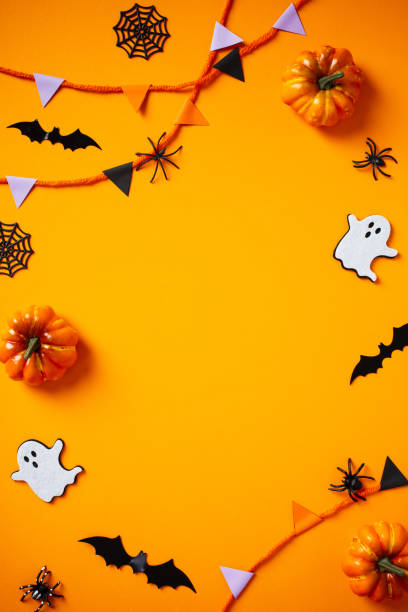 istock Halloween frame of bunting, ghosts, pumpkins, web, bats, spiders on orange background. Flat lay, top view,, copy space. 2174590030