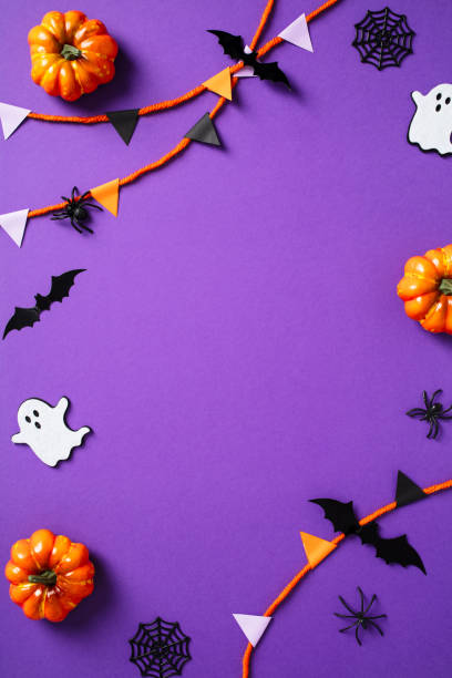 istock Halloween frame of bunting, ghosts, pumpkins, web, bats, spiders on purple background. Flat lay, top view,, copy space. 2174590162