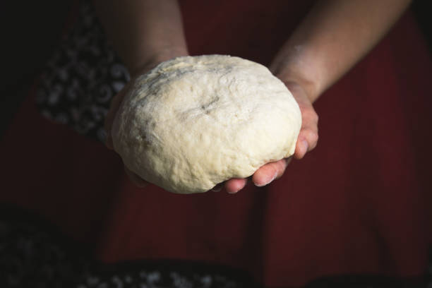 istock Woman's hands holding dough over kitchen board, warm photo of home baking process. 2174594693