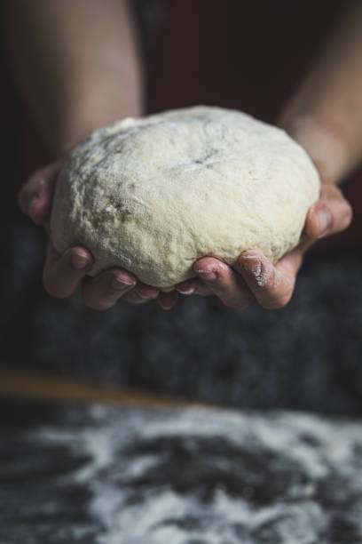 istock Woman's hands holding dough over kitchen board, warm photo of home baking process. 2174594708