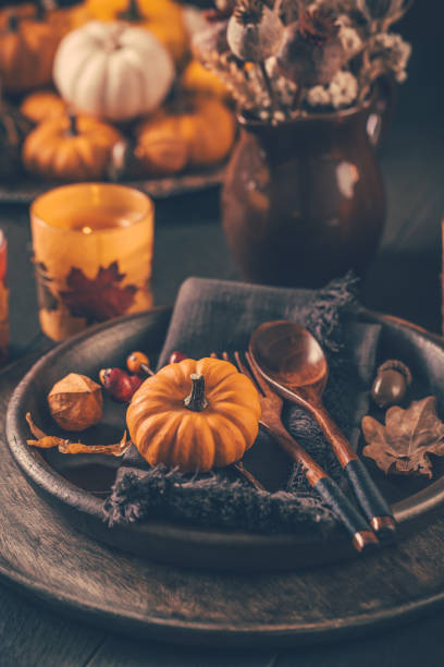 Place setting, festive Thanksgiving table setting with pumpkins and candles in brown tone