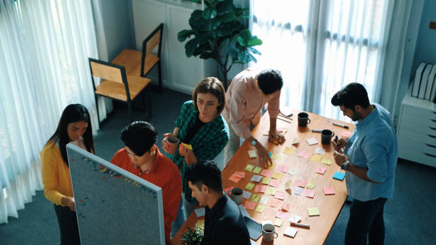 istock Top view of diverse people writing and stick sticky notes at board. Convocation. 2174606896