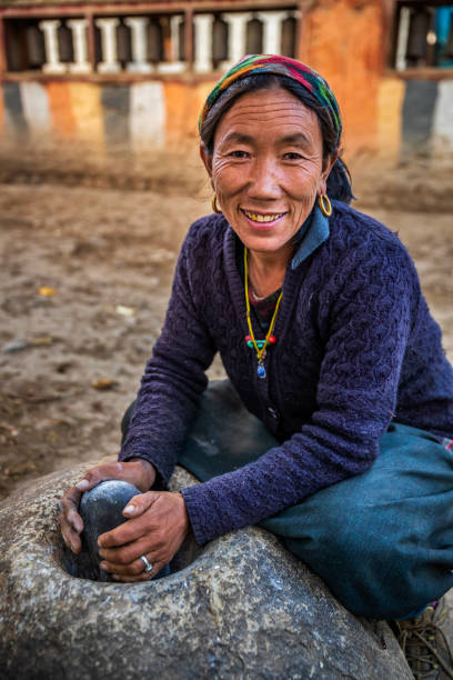 istock Tibetan woman using a stone mortar to make flour, Upper Mustang, Nepal 2174607771