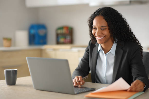 Happy black busineswoman working online in the kitchen stock photo