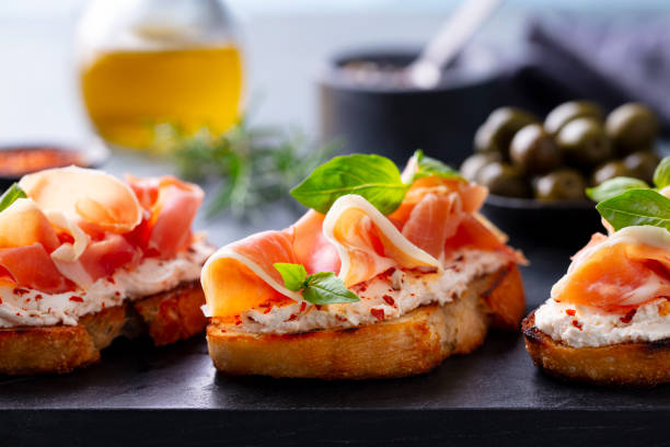 istock Bruschetta, crostini with Jamon, ham and fresh basil on dark marble board. Close up. 2174608306