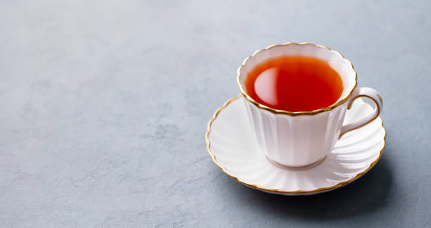 istock Tea in white cup with gold rim. Grey background. Copy space. 2174608551
