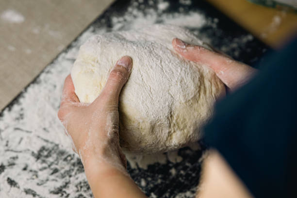 istock The process of kneading yeast dough on a kitchen board at home, woman's hands. 2174609425