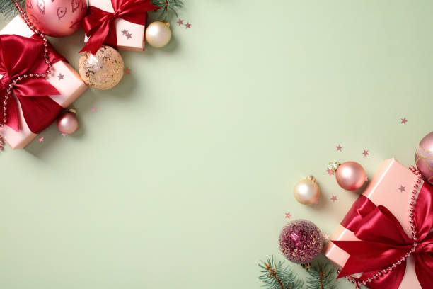istock Festive Christmas background with gift boxes, baubles, and green fir branches on a light green backdrop 2174609432