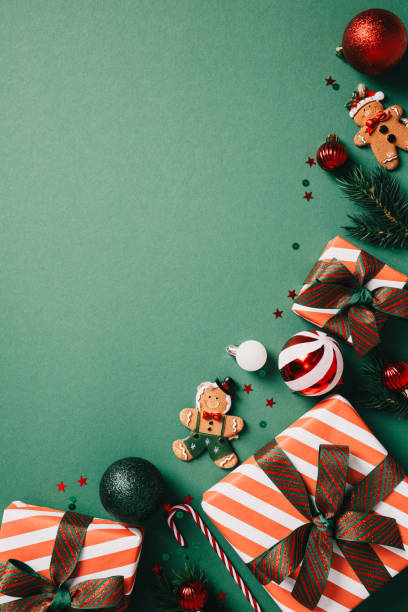 istock Christmas or winter holidays flat lay composition featuring wrapped gifts, a gingerbread cookie, and Christmas ornaments on a green background 2174609783