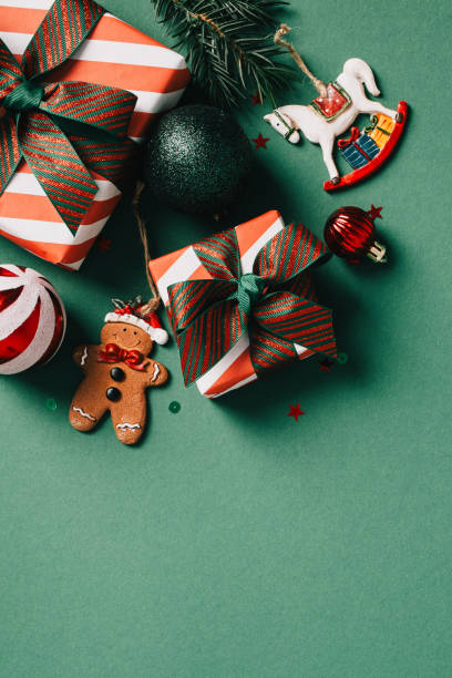 istock Christmas gifts and ornaments on green backdrop. Includes wrapped presents, gingerbread man, baubles, stars, pine branch, and rocking horse. Perfect for holiday themes and celebrations. 2174610467