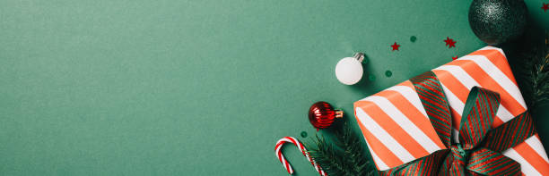 istock Festive Christmas Decorations: Bright holiday-themed image with a striped gift box, red and green ornaments, and candy canes on a green background. Ideal for seasonal promotions and festive content 2174610660