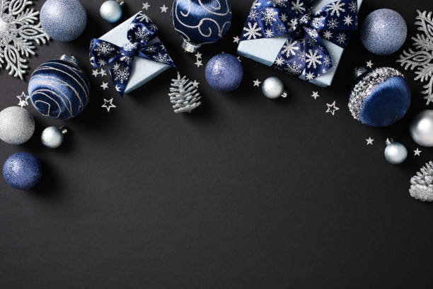 istock Frame of elegant Christmas decorations in blue and silver, featuring baubles, gift boxes, snowflakes, and pine cones on a dark background 2174611699