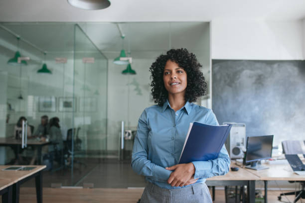 istock Smiling young businesswoman holding files while standing in an office 2174624227