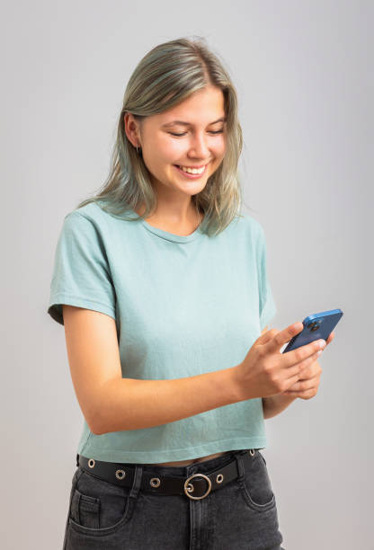 istock Young girl using her smartphone, texting, using app. Isolated on gray background. 2174625066