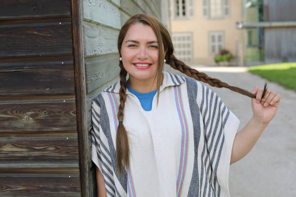 A Hispanic woman in her thirties is walking around in a village. She wears a traditional Colombian poncho called 
