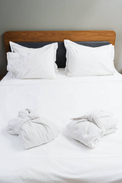 istock Comfortable Bed With Bathrobes For Bedtime Rest And Spa Relaxation 2174631725