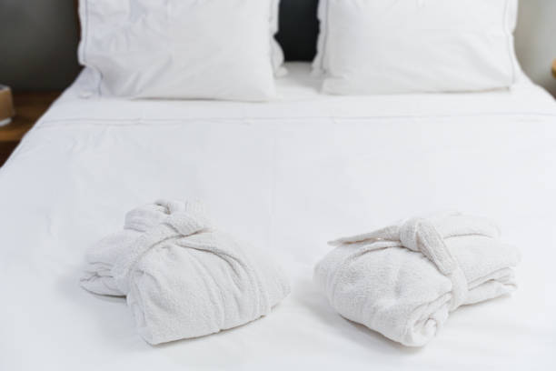 istock Two Soft White Bathrobes Placed On Clean Cozy White Bed 2174631730