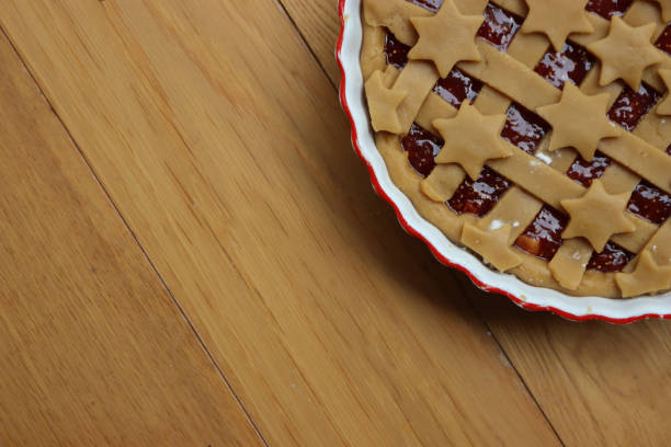 Tart with dark fig jam in a white ceramic cake pan on wooden table ready to be baked