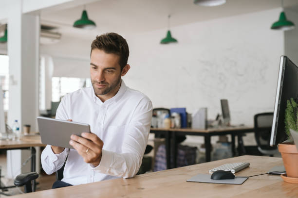 istock Young businessman sitting at his desk using a digital tablet 2174637002