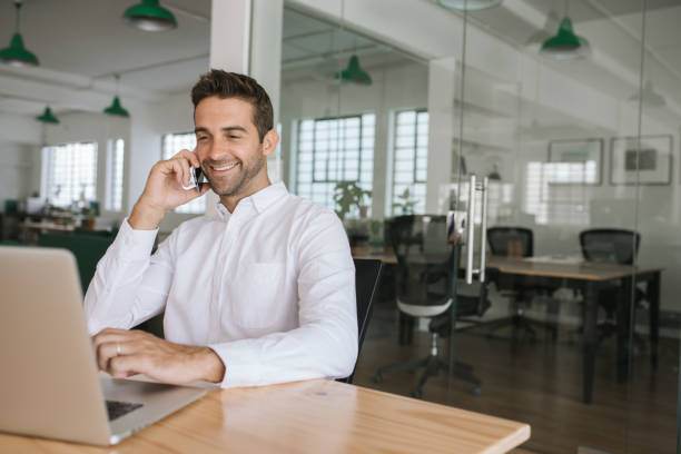 istock Smiling businessman talking on a cellphone and using his laptop 2174637158