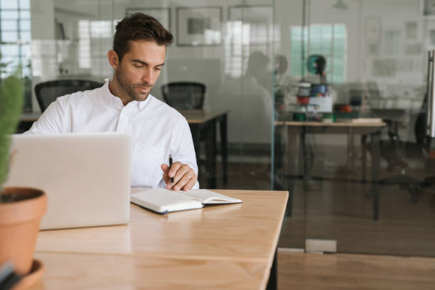 istock Young businessman working on a laptop and writing down notes 2174639439