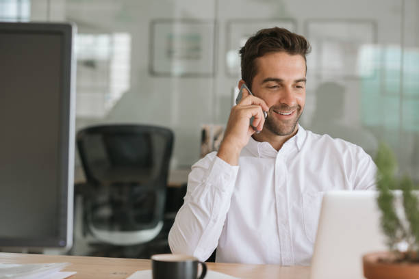 istock Smiling businessman talking on a cellphone at his office desk 2174641611