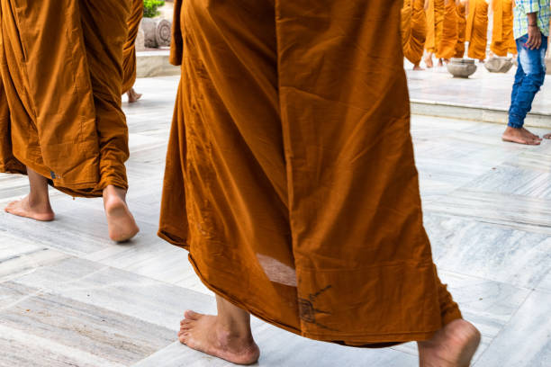 Buddhist monks walking barefoot in traditional saffron robes inside a temple in india