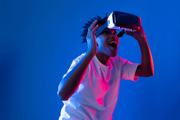 istock Surprised African looking VR holding object hologram neon wall. Contrivance. 2174647638