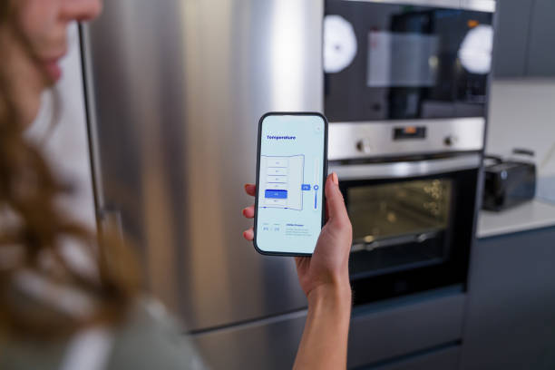 istock Woman controlling refrigerator temperature with mobile app in modern kitchen 2174658365