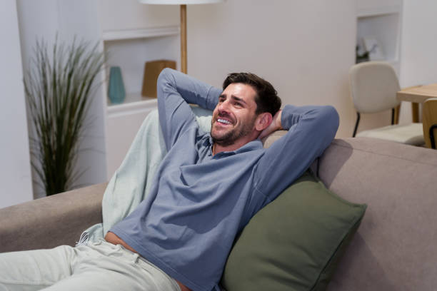 istock Happy man relaxing on sofa at home in living room 2174659356