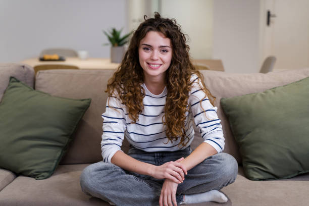 istock Young woman smiling while relaxing on sofa at home 2174659402