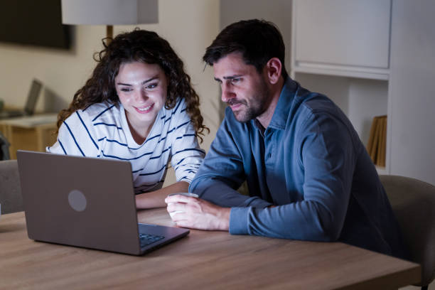 istock Happy young couple using laptop together browsing internet at home 2174659693