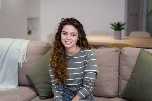 istock Young woman smiling while relaxing on sofa at home 2174659850