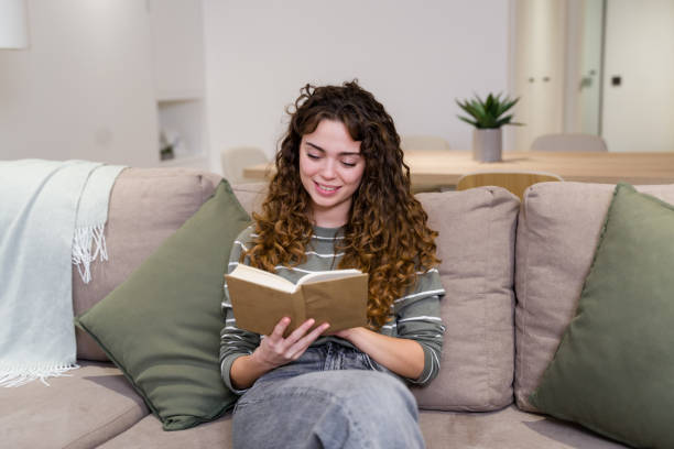 istock Young woman enjoying a book on a comfortable sofa at home 2174659920