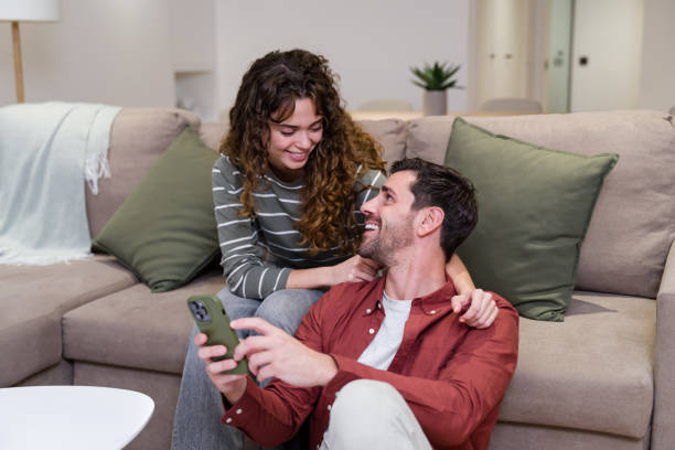 istock Happy couple relaxing on the floor at home using smartphone 2174660088