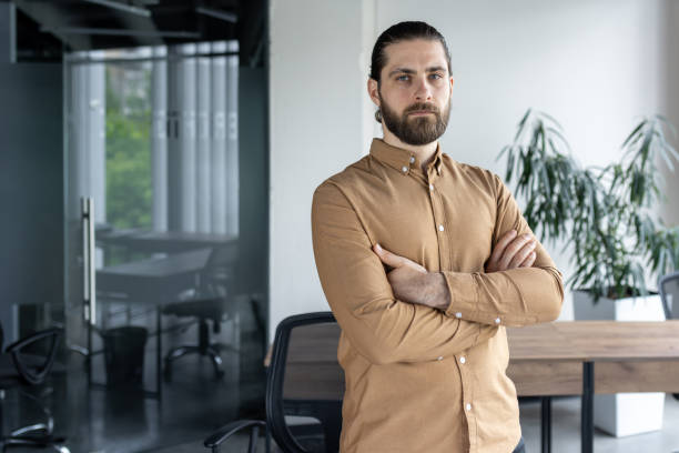 istock Confident businessman standing with arms crossed in modern office setting with natural light 2174660176