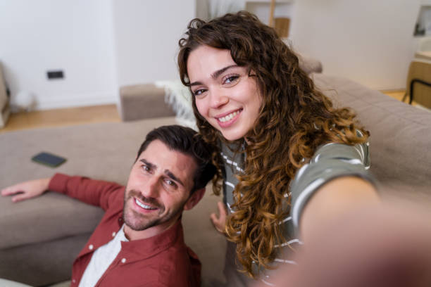 istock Young couple relaxing on sofa taking a selfie together 2174660183