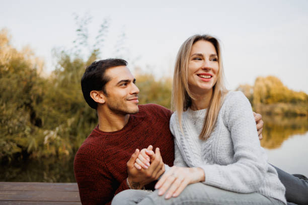 istock Young couple in sweaters relaxing on pier in autumn 2174661455