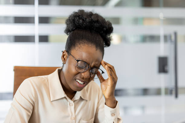 istock African American businesswoman experiencing stress at work, feeling a headache while sitting in a modern office setting, adjusting glasses for relief 2174661712