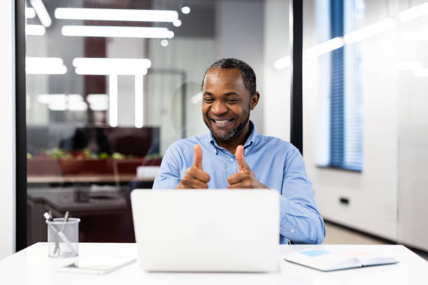 istock Smiling businessman giving thumbs up while having successful video call in modern office environment 2174662617
