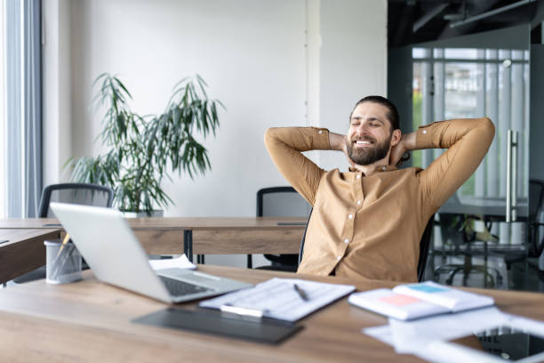 istock Relaxed businessman enjoying a break in modern office with laptop and documents on desk 2174664450