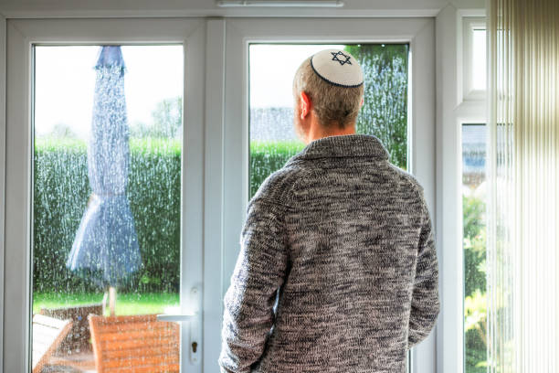 istock Jewish man wearing yarmulke looking through rainy window 2174666506