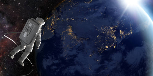 Astronaut in outer space on tethered space walk looking at the sun coming over planet earth on which city lights are visible.  Credit: NASA https://earthobservatory.nasa.gov/images/79790/city-lights-of-asia-and-australia and ESO for earth/stars.