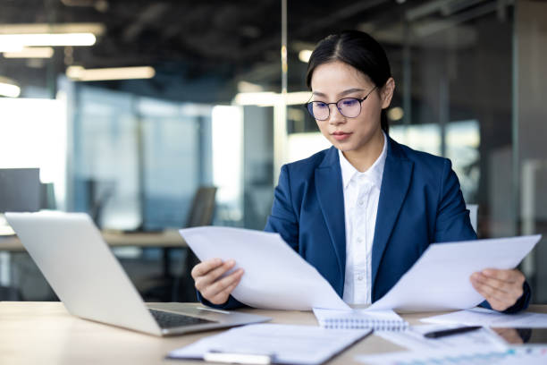 istock Serious financial professional reviewing documents in modern office environment at desk with laptop and papers 2174669057