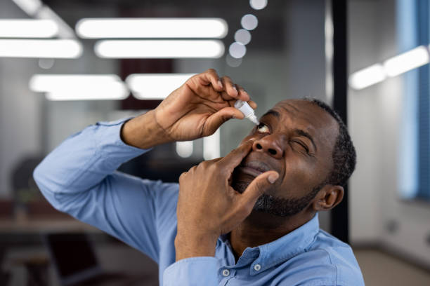 istock African American mature businessman using eye drops for relief during a busy workday in modern office environment 2174671051