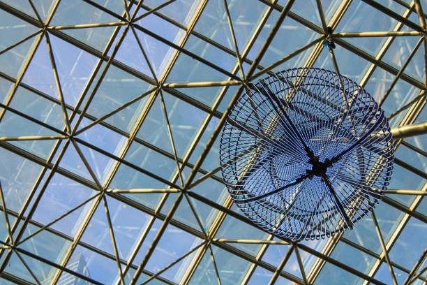 There is a striking blue sculpture gracefully hanging from the ceiling of a modern building, attracting the attention of passersby and visitors alike